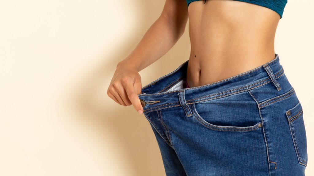 A woman showing her loosen pants after weight loss by eating vegan diet